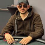 Ein Bild von einem Pokertisch mit Spielkarten, Chips und verschiedenen Spielern, die ihre Karten betrachten.