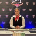 Ein professioneller Pokerspieler sitzt an einem Spieltisch und hält Karten in der Hand, während er konzentriert auf seine Gegner schaut.
