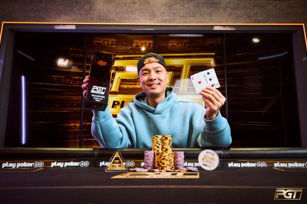 Ein Mann sitzt an einem Pokertisch und betrachtet seine Karten. Im Hintergrund sind andere Spieler zu sehen.