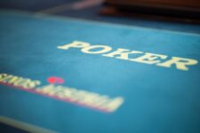 Ein Mann und eine Frau spielen Poker an einem Tisch in einem eleganten Casino. Der Mann hat Karten in der Hand und schaut konzentriert auf den Tisch, während die Frau mit einem Pokerchip spielt und lächelt