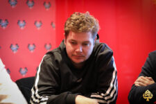 Ein Mann namens Oliver Weis sitzt lächelnd an einem Pokertisch und hält Karten in der Hand. Sein Blick ist konzentriert und selbstbewusst.