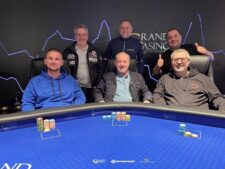 Ein Poker-Turniertisch mit grünen Filz und Chips, auf denen das Progressive Bounty-Logo zu sehen ist. Es liegen Karten und Dealer-Buttons auf dem Tisch, der von Spielern umgeben ist.