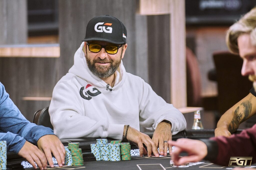 Ein Mann sitzt an einem Pokertisch und betrachtet konzentriert seine Karten. Im Hintergrund sind andere Spieler und Dealer zu sehen. Das Bild zeigt Daniel Negreanu beim Spielen in einem Mixed-Game-T