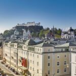 Ein elegantes Hotel mit Blick auf den Fluss in Salzburg, Österreich. Die historische Architektur und die malerische Umgebung sorgen für eine idyllische Atmosphäre.