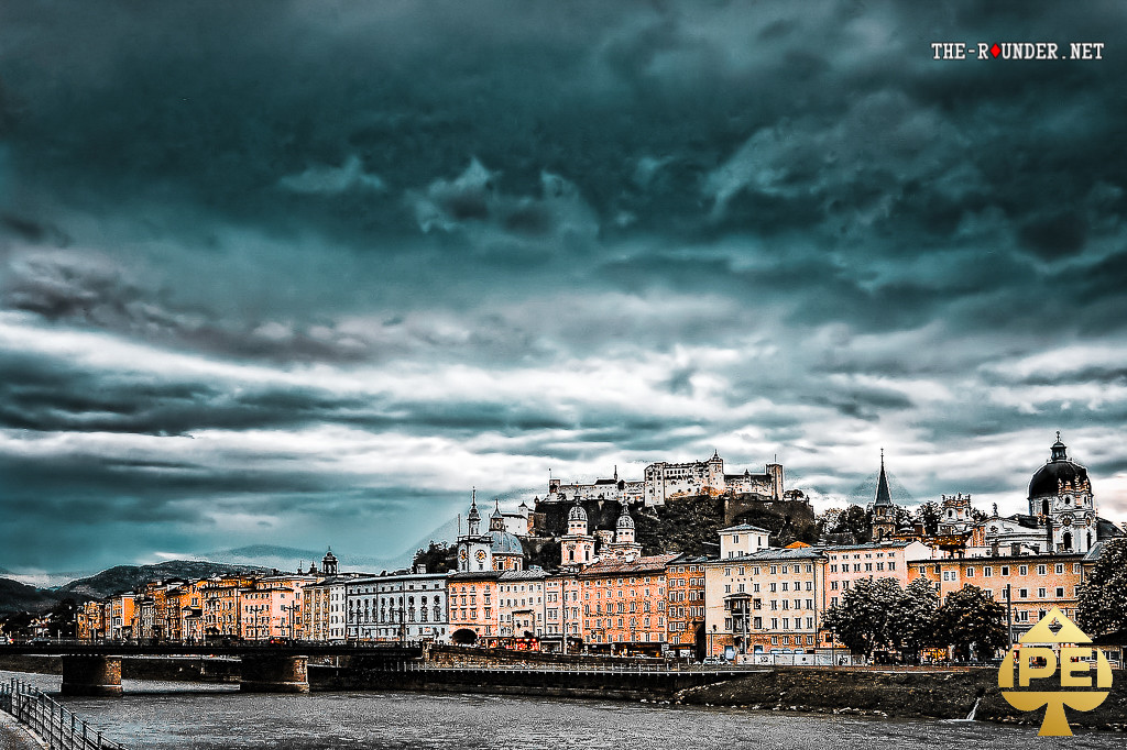 Ein atemberaubendes Panorama von Salzburg mit der Festung Hohensalzburg und der malerischen Altstadt, umgeben von grünen Hügeln und einem blauen Himmel.