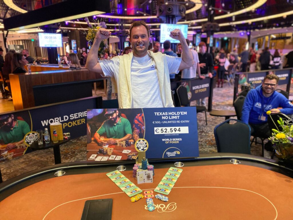 Ein Mann mit einem grünen Hoodie und schwarzer Baseballmütze jubelt über seinen Sieg beim No-Limit Hold'em Turnier mit einem Buy-In von 500 $. Er hält stolz eine Trophäe in