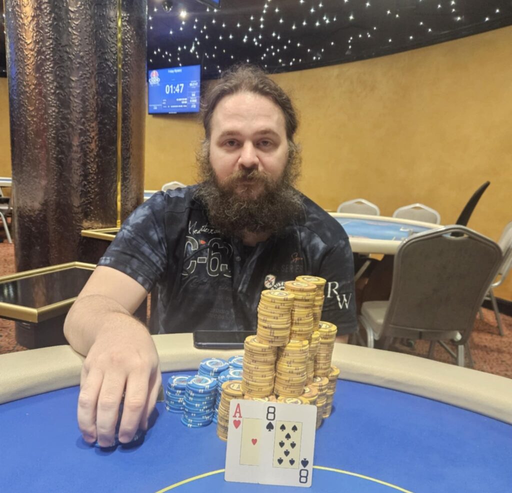 Ein bunter und lebendiger Pokertisch mit Stapeln von Pokerchips, Spielkarten und Getränken, umgeben von Spielern in einem Casino.