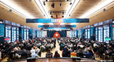 Ein vollbesetzter Pokerraum mit zahlreichen Spielern an den Tischen, die konzentriert ihre Karten betrachten. Die Atmosphäre ist lebhaft und die Spannung ist förmlich spürbar.