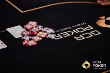 Ein professioneller Pokertisch mit grüner Filzoberfläche, umgeben von gepolsterten Stühlen und beleuchtet von einer eleganten Deckenleuchte. Die Tischmitte zeigt Spielkarten,