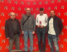 Ein Gruppenfoto von Pokerspielern, die an einem Tisch sitzen und Karten spielen in einem eleganten Pokerraum mit gedämpfter Beleuchtung und stilvoller Einrichtung.