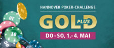 Ein goldener Pokerchip auf einem grünen Pokertisch mit Spielkarten im Hintergrund.
