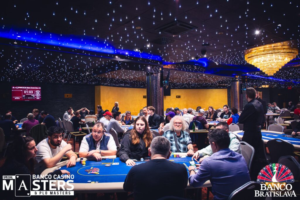 Ein professioneller Pokerspieler sitzt an einem Tisch während eines Turniers und betrachtet konzentriert seine Karten. Um ihn herum sind weitere Spieler und Zuschauer zu sehen. Die Spannung ist förmlich