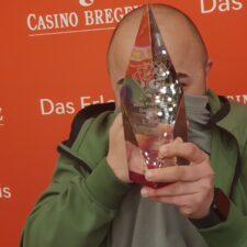 Ein Foto eines Pokerturniers im Frühling vor dem Hintergrund des Bodensees in Bregenz. Spieler sitzen an einem Tisch und konzentrieren sich auf ihre Karten. Die Sonne scheint und die Atmos