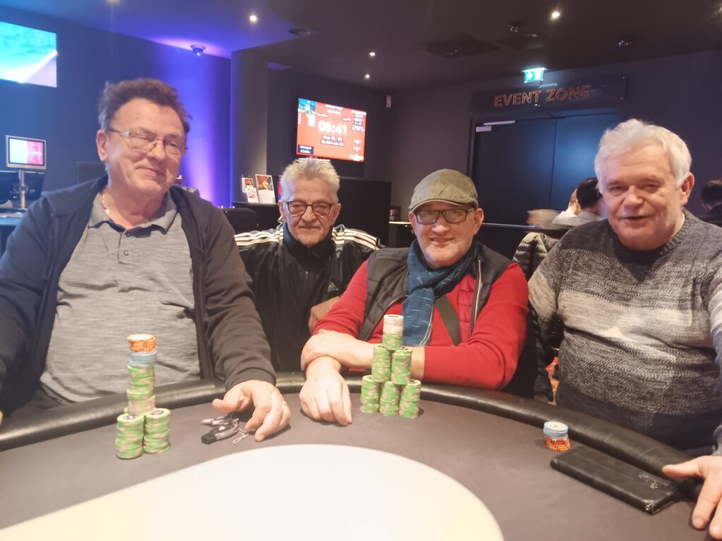 Ein Mann und eine Frau spielen Poker an einem Tisch in einem gemütlichen Raum mit roten Wänden und gedimmtem Licht.