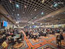 Ein voll besetzter Raum bei der World Series of Poker, mit vielen Pokertischen und Spielern, die konzentriert Karten spielen.