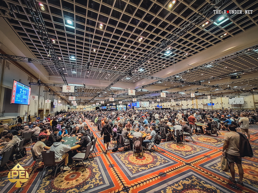 Ein voll besetzter Raum bei der World Series of Poker, mit vielen Pokertischen und Spielern, die konzentriert Karten spielen.