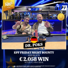Ein Mann sitzt an einem Pokertisch und hält zwei Spielkarten in der Hand. Er schaut konzentriert auf den Tisch, auf dem Pokerchips und Karten liegen. Im Hintergrund sind andere Spieler