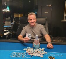 Ein farbenfroher Poker-Tisch mit Spielkarten, Pokerchips und Getränken, umgeben von einer Gruppe von Menschen, die lächelnd miteinander interagieren.