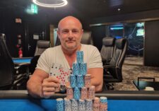 Ein professionell gestalteter Pokertisch mit grünem Filz, umgeben von Spielkarten, Pokerchips und Getränken. Ein Spieler mit Sonnenbrille und Kappe sitzt am Tisch und studiert