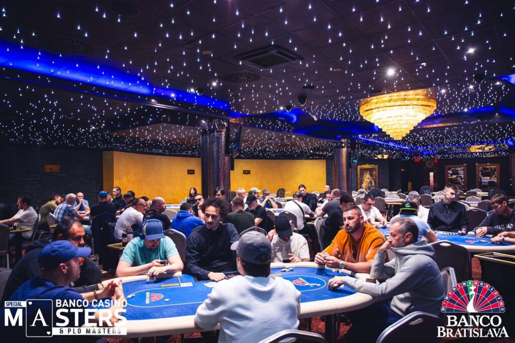 Ein Mann und eine Frau sitzen an einem Pokertisch und spielen gegeneinander. Der Mann hat eine Hand mit Pokerchips vor sich, während die Frau ihre Karten betrachtet. Beide haben konzentrierte Gesicht