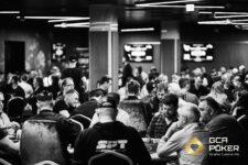 Ein Mann und eine Frau sitzen an einem Pokertisch im Casino. Der Mann mischt die Karten, während die Frau ihre Karten ansieht und konzentriert wirkt. Die Szene ist in einem eleganten Raum mit
