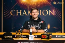 Ein Mann sitzt an einem Pokertisch und hält stolz eine Trophäe in die Luft, umringt von jubelnden Zuschauern.
