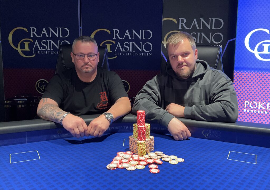 Ein Mann und eine Frau sitzen an einem Pokertisch und spielen eine Partie Poker. Der Mann hält Karten in der Hand und schaut konzentriert auf den Tisch, während die Frau ihm gegenüber mit ernstem Ges