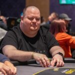 Ein bunter Pokertisch mit grüner Filzoberfläche, umgeben von Spielkarten, Pokerchips und Getränken. In der Mitte des Tisches befindet sich eine Gruppe von Menschen, die kon