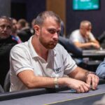 Ein Mann und eine Frau sitzen an einem Pokertisch und spielen Texas Hold'em. Der Mann hat eine Hand aus Karten und Chips vor sich liegen, während die Frau konzentriert auf ihre eigenen Karten schaut. Im H