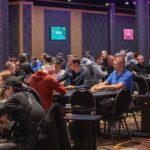 Ein Mann und eine Frau sitzen an einem Pokertisch und spielen Karten. Der Mann hat einen Stapel Chips vor sich, während die Frau ihre Karten betrachtet. Das Bild zeigt eine entspannte und konzentrierte Atmos