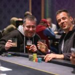 Ein Stapel von Pokerchips in verschiedenen Farben und Werten, der auf einem grünen Pokertisch liegt.