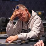 Ein Mann und eine Frau sitzen an einem Pokertisch und spielen eine Runde Poker. Der Mann hält Karten in der Hand, während die Frau mit konzentriertem Gesichtsausdruck auf ihre Karten schaut