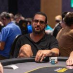 Ein grüner Pokertisch mit Spielkarten, Pokerchips und zwei Spielern, die ihre Karten halten.