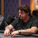 Ein Stapel von Pokerchips in verschiedenen Farben und Werten liegt auf einem grünen Pokertisch.