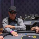 Auf dem Bild ist ein Pokertisch zu sehen, an dem mehrere Personen Karten spielen. Die Spieler sitzen um den Tisch herum und konzentrieren sich auf ihre Karten. Es herrscht eine entspannte Atmos