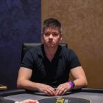 Ein buntes Pokerspiel mit Spielkarten, Jetons und Getränken auf einem Tisch.