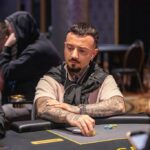 Ein Mann und eine Frau sitzen an einem Pokertisch und spielen Texas Hold'em. Der Mann hat eine Hand mit Karten und Chips vor sich, während die Frau konzentriert auf ihre Karten schaut. Der Tisch ist mit