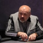 Ein Spieler hält zwei Karten mit einem Pokerchip-Stack im Hintergrund.
