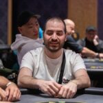 Ein buntes Pokerspiel mit Spielkarten, Jetons und Pokerchips auf einem grünen Pokertisch.