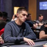Ein Mann und eine Frau sitzen an einem Pokertisch und spielen Karten. Der Mann hält seine Karten in der Hand, während die Frau konzentriert auf ihre Karten schaut. Im Hintergrund sind Pokerchips