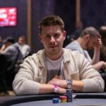 Ein Mann und eine Frau spielen Poker an einem eleganten Tisch in einem stilvollen Raum mit Pokerchips und Karten vor sich.