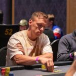 Ein Mann und eine Frau spielen Poker an einem eleganten Tisch in einem stilvoll eingerichteten Raum. Die Frau hat gerade eine Hand gewonnen und strahlt vor Freude, während der Mann leicht enttäuscht auss