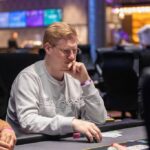 Ein Paar Karten, die auf einem grünen Pokertisch liegen, umgeben von Pokerchips in verschiedenen Farben und Stapeln von Jetons.