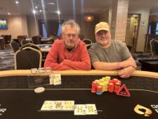 Ein Mann und eine Frau sitzen an einem Pokertisch, beide konzentriert auf ihre Karten. Der Mann hat eine Hand am Kinn und schaut nachdenklich, während die Frau ihre Karten prüft. Die