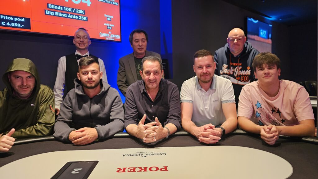 Ein Mann und eine Frau sitzen an einem Pokertisch mit Chips und Karten. Der Mann schaut konzentriert auf seine Karten, während die Frau mit einem Pokerface in die Kamera lächelt.