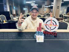 Ein Mann und eine Frau spielen Poker an einem Tisch in einem eleganten Casino. Der Mann hat eine Hand mit Karten, während die Frau konzentriert auf ihre Karten schaut. Hinter ihnen sind andere Spieler und eine Dealerin