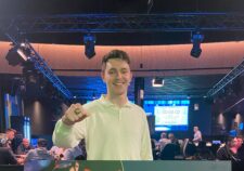 Ein Bild eines Pokertisches während eines Turniers mit vielen Stapeln von Pokerchips und Spielkarten, die von verschiedenen Spielern gehalten werden.
