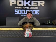 Ein Mann hält stolz eine Trophäe in die Luft, während er lächelnd vor einem Pokertisch steht.