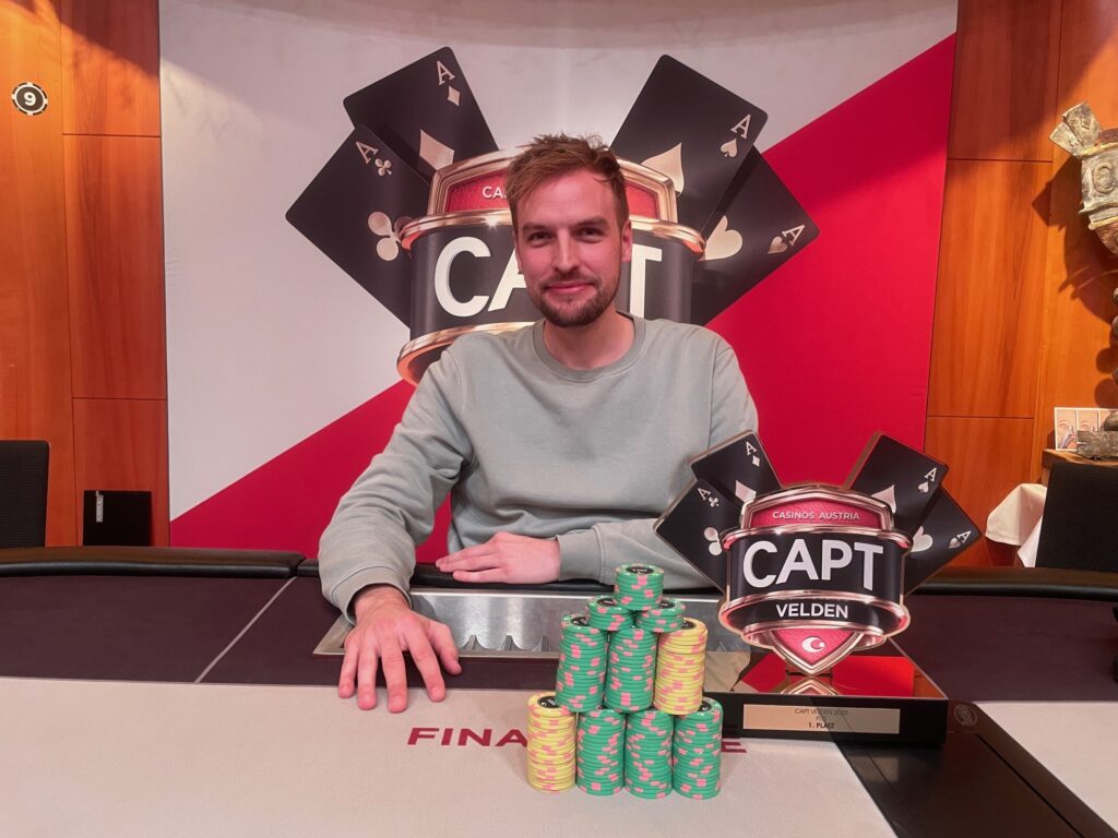 Ein Pokertisch mit vier Spielern, die Texas Hold'em spielen. Ein Spieler hat eine Hand mit vier Pik-Karten, während ein anderer Spieler seine Chips in die Mitte schiebt. Die Atmosphäre ist konzentriert