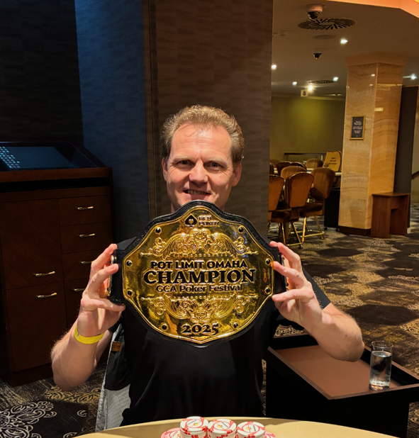 Ein Pokertisch mit Spielkarten und Pokerchips darauf, umgeben von vier Personen, die konzentriert spielen.